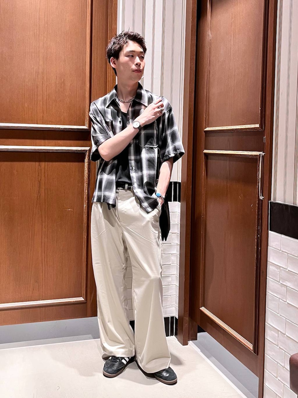 ホワイト系のスラックス、ブラック系のショルダーバッグ、ブラック系のシャツ/ブラウスを着用したメンズの夏コーディネートの6枚目の写真