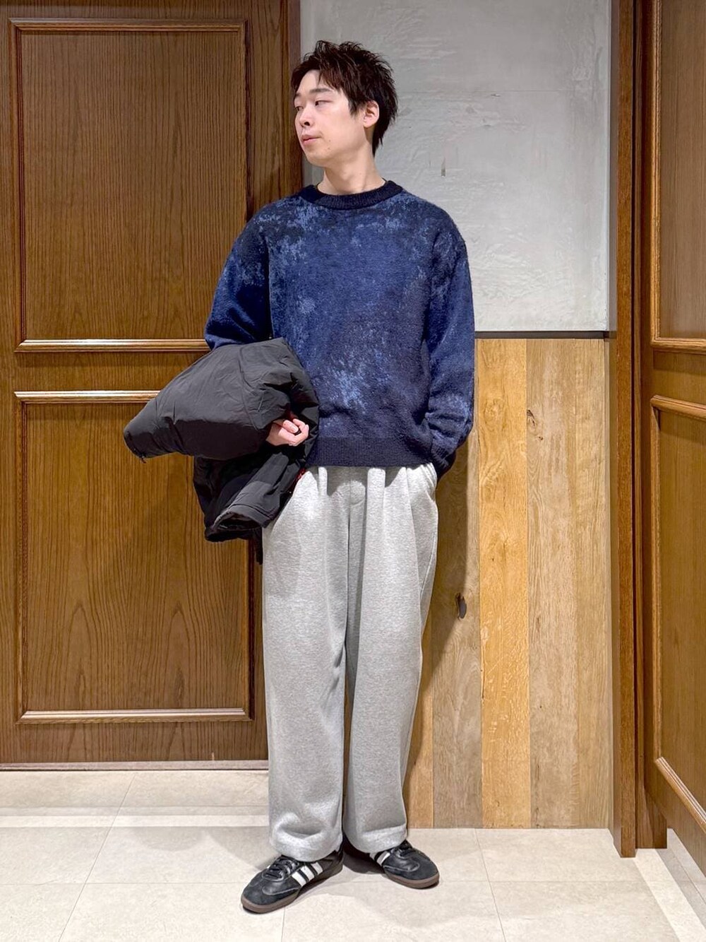 ブラック系のダウンジャケット/コート、ブルー系のニット/セーター、グレー系のスウェットパンツを着用したメンズの冬コーディネートの7枚目の写真