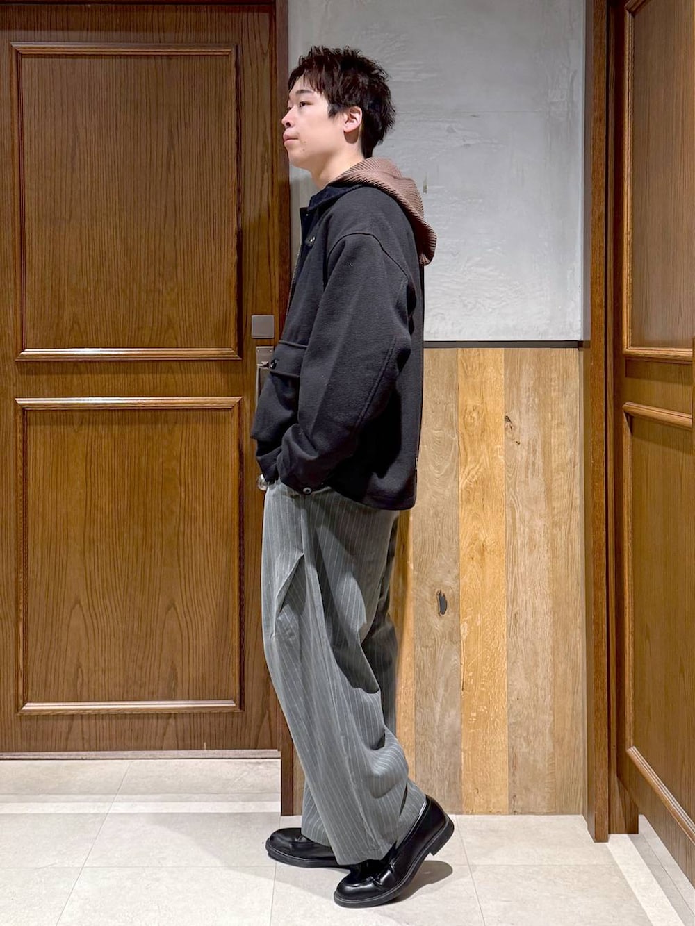 ブラック系のブルゾン、ブラウン系のニット/セーター、グレー系のスラックスを着用したメンズの冬コーディネートの6枚目の写真