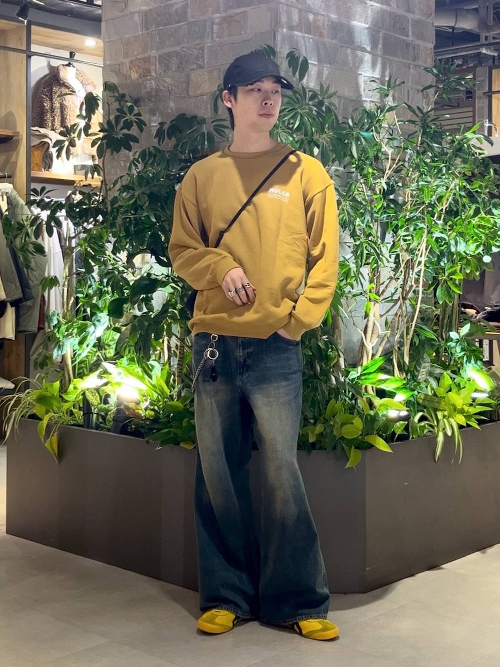 ブラック系のショルダーバッグ、ブルー系のデニムパンツ、イエロー系のスウェットを着用したメンズの秋コーディネートの3枚目の写真