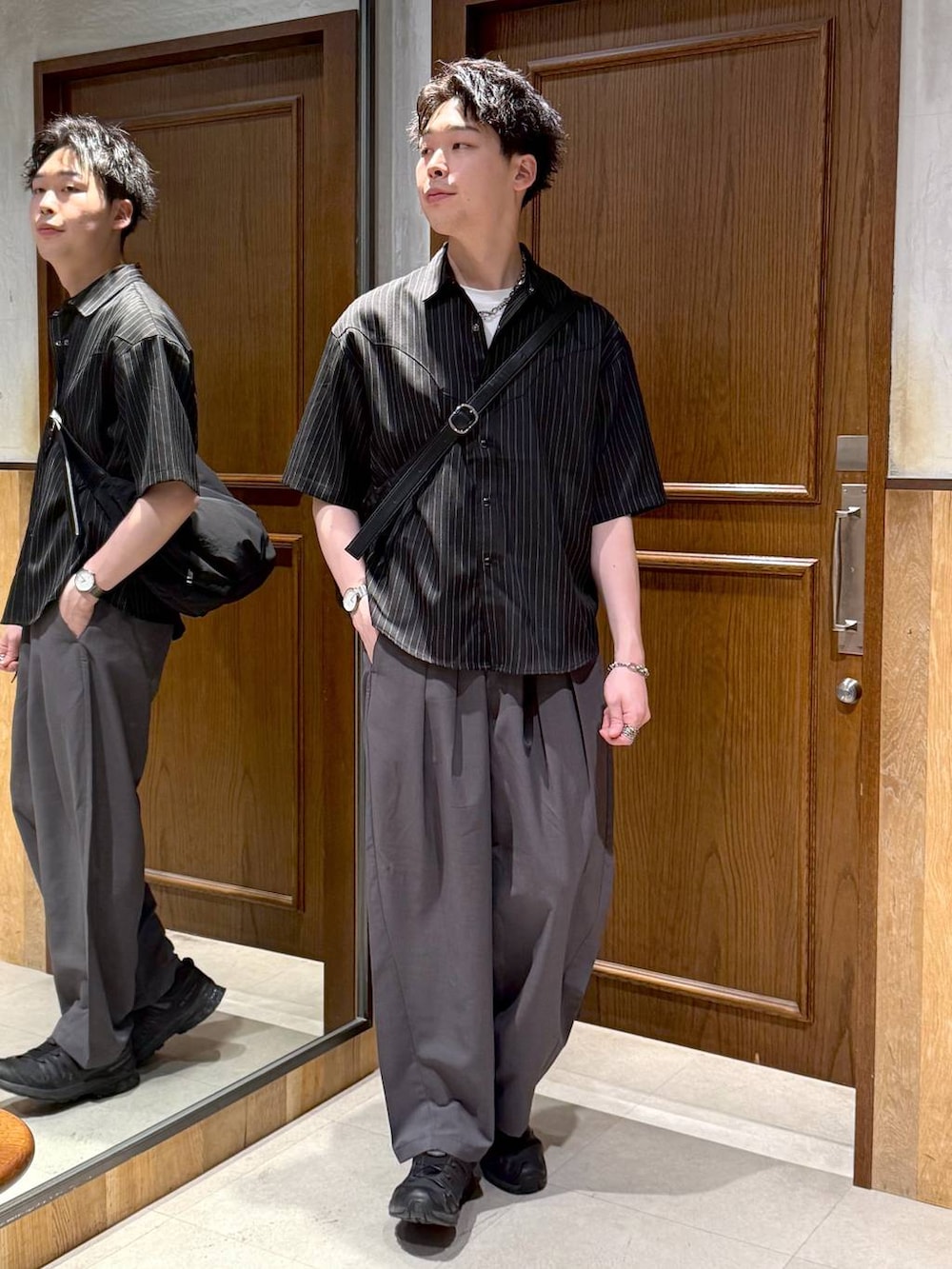 グレー系のスラックス、ブラック系のショルダーバッグ、ホワイト系のTシャツ/カットソーを着用したメンズの春コーディネートの2枚目の写真