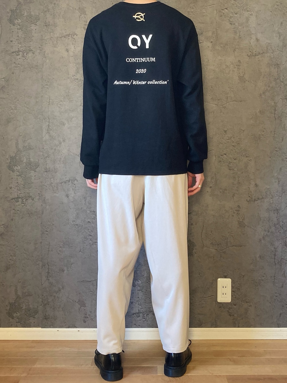 ブラック系のTシャツ/カットソー、ホワイト系のスラックス、ブラック系のドレスシューズを着用したメンズの秋コーディネートの2枚目の写真