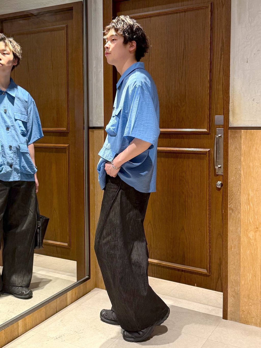 ブラック系のハンドバッグ、ブラック系のデニムパンツ、ブルー系のシャツ/ブラウスを着用したメンズの春コーディネートの3枚目の写真