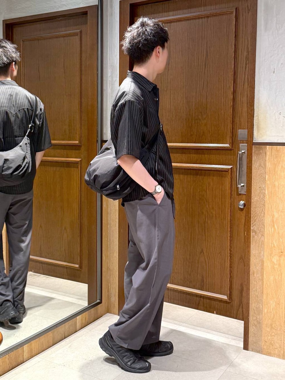 グレー系のスラックス、ブラック系のショルダーバッグ、ホワイト系のTシャツ/カットソーを着用したメンズの春コーディネートの5枚目の写真
