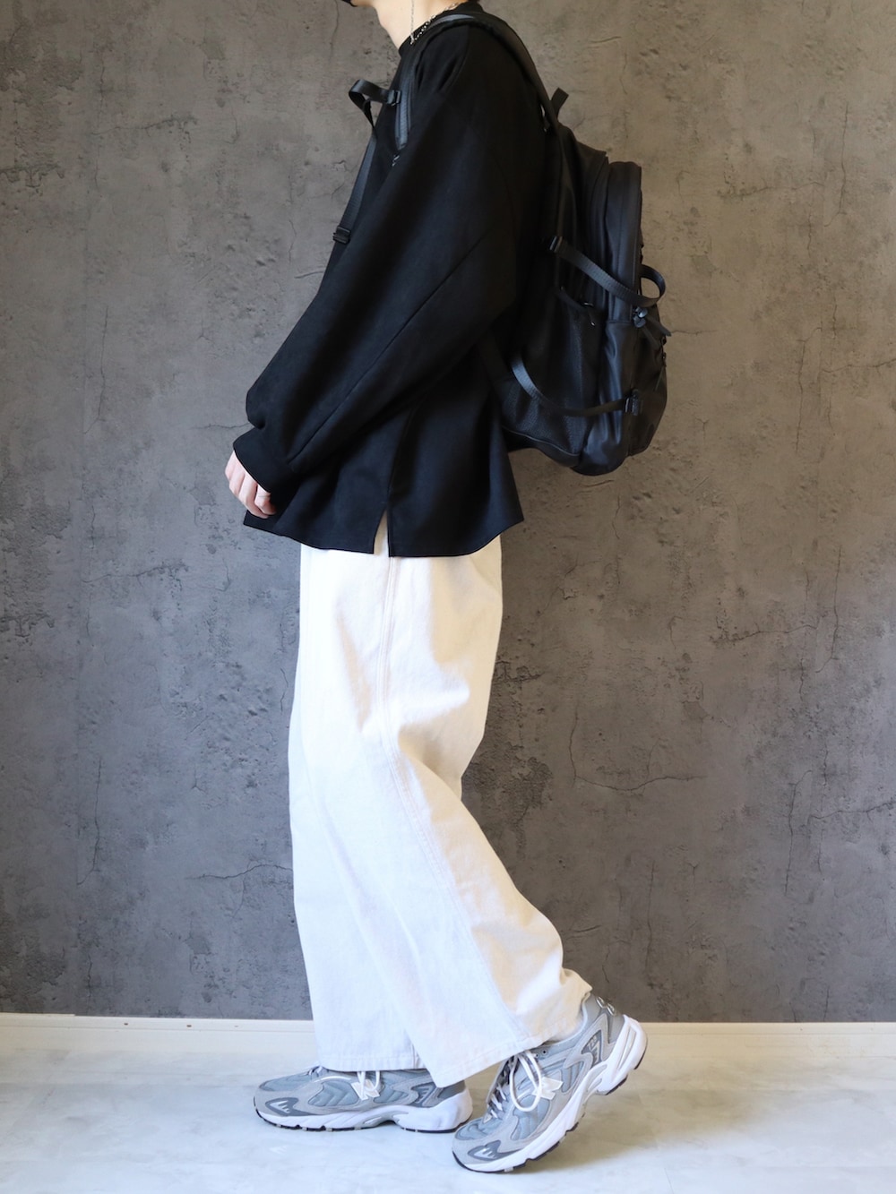 ブラック系のスウェット、ホワイト系のスラックス、グレー系のスニーカーを着用したメンズの春コーディネートの3枚目の写真