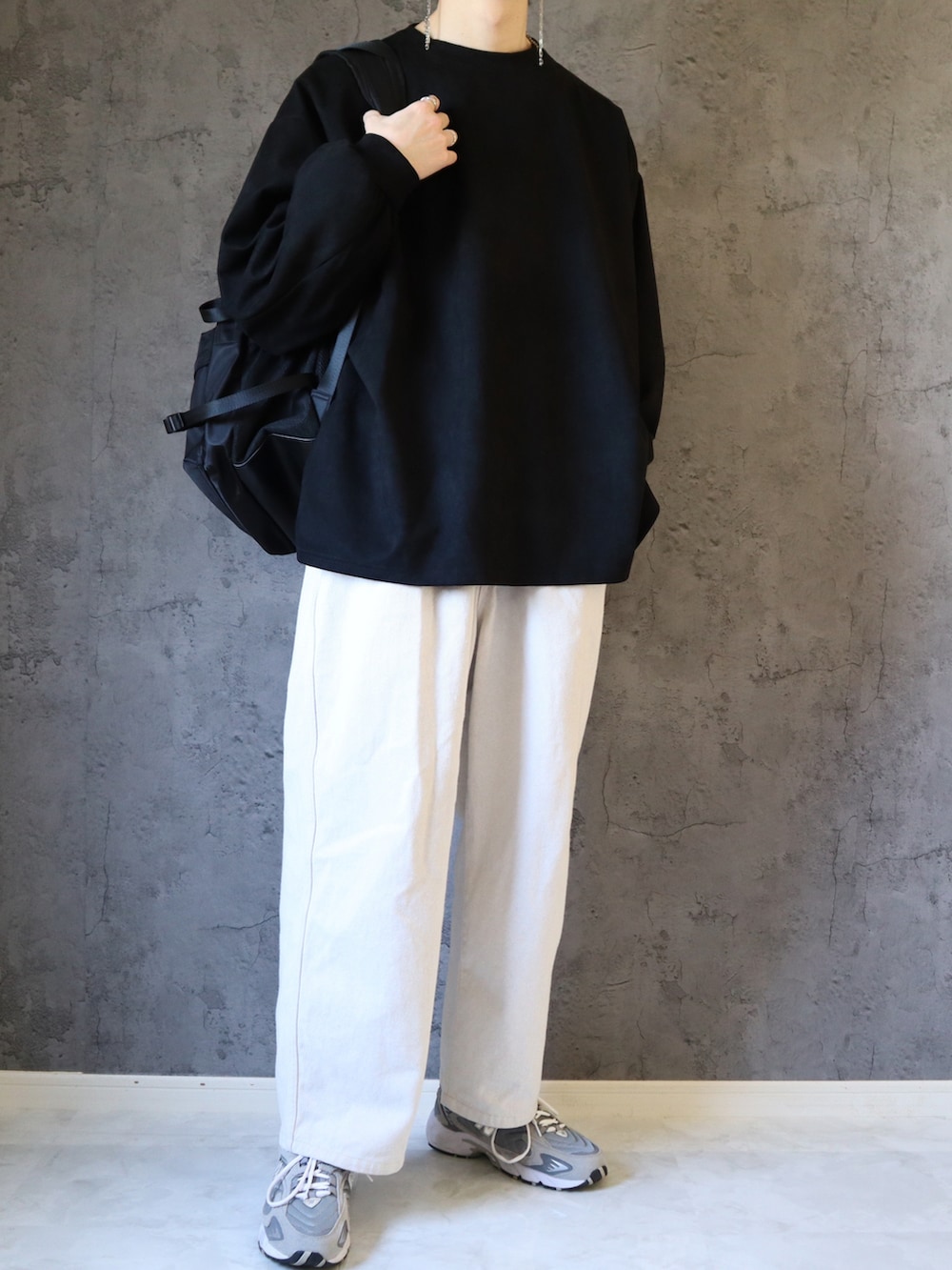 ブラック系のスウェット、ホワイト系のスラックス、グレー系のスニーカーを着用したメンズの春コーディネートの5枚目の写真