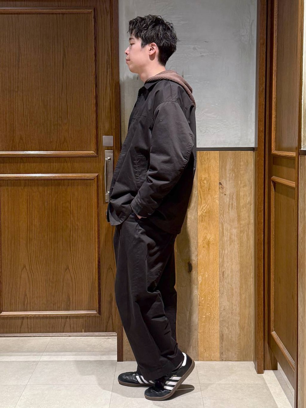 ブラック系のチノパンツ、ブラック系のステンカラーコート、ブラウン系のニット/セーターを着用したメンズの冬コーディネートの3枚目の写真