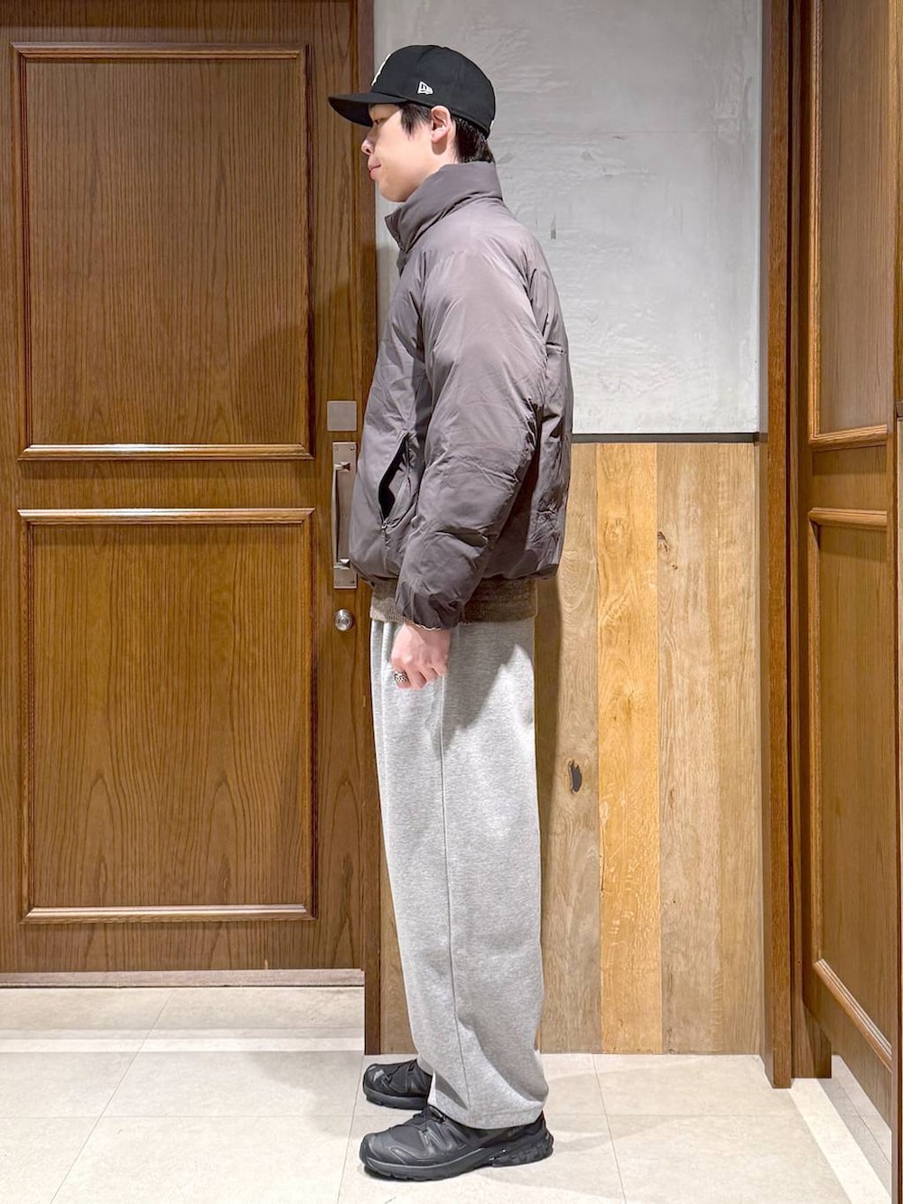 グレー系のダウンジャケット/コート、ベージュ系のポロシャツ、グレー系のスウェットパンツを着用したメンズの冬コーディネートの5枚目の写真