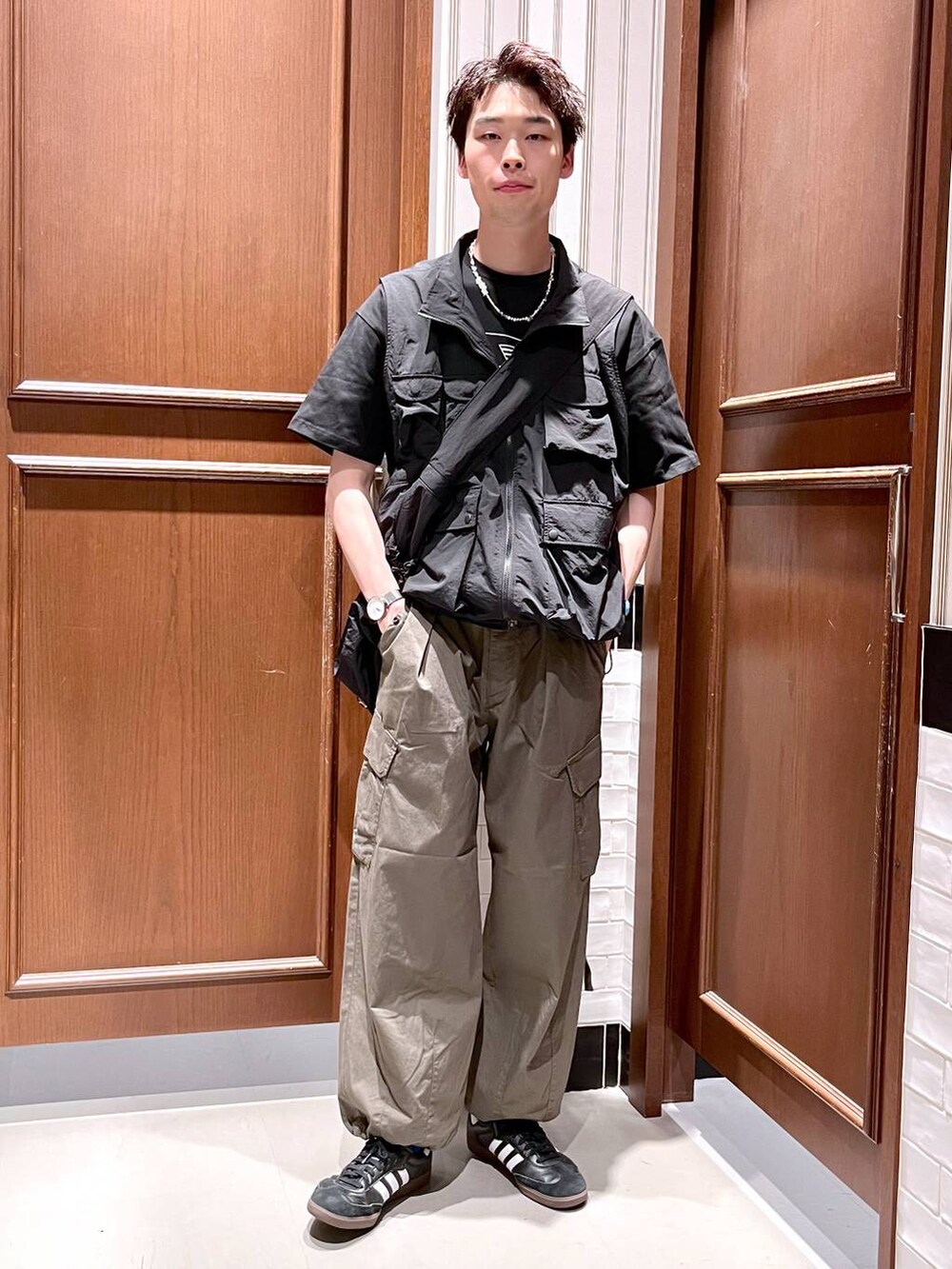 グリーン系のカーゴパンツ、ブラック系のショルダーバッグ、ブラック系のベストを着用したメンズの夏コーディネートの6枚目の写真