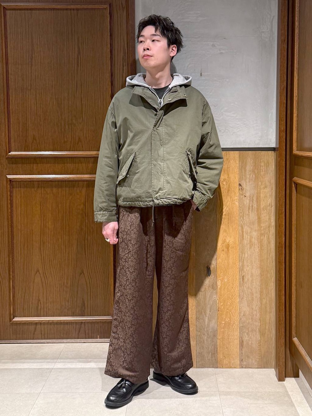 グリーン系のモッズコート、イエロー系のスラックス、グレー系のパーカーを着用したメンズの冬コーディネートの7枚目の写真