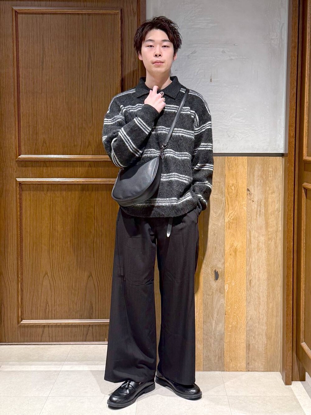 ブラック系のショルダーバッグ、ブラック系のポロシャツ、ブラック系のスラックスを着用したメンズの冬コーディネートの2枚目の写真