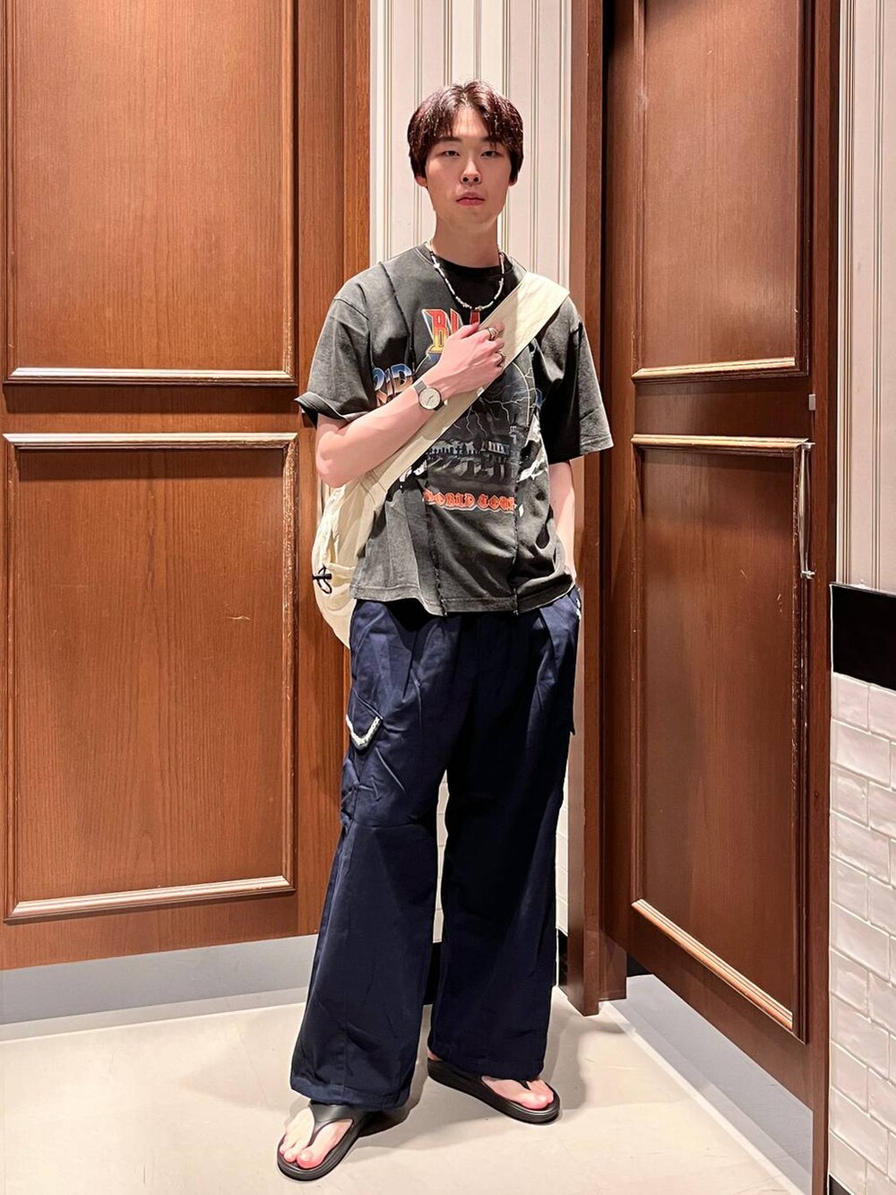 ブラック系のサンダル、ブルー系のカーゴパンツ、ホワイト系のショルダーバッグを着用したメンズの夏コーディネートの6枚目の写真