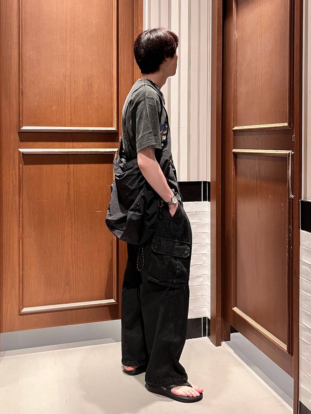 グレー系のデニムパンツ、ブラック系のショルダーバッグ、ブラック系のサンダルを着用したメンズの夏コーディネートの5枚目の写真