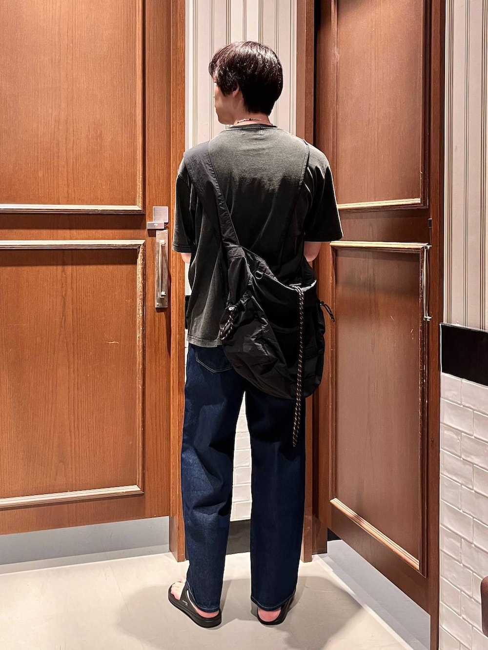 ブラック系のサンダル、ブルー系のデニムパンツ、ブラック系のショルダーバッグを着用したメンズの夏コーディネートの5枚目の写真