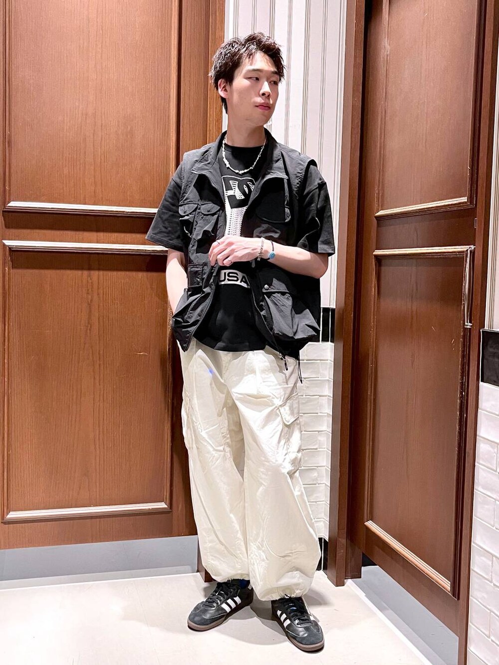 ホワイト系のカーゴパンツ、ブラック系のベスト、ブラック系のTシャツ/カットソーを着用したメンズの夏コーディネートの3枚目の写真
