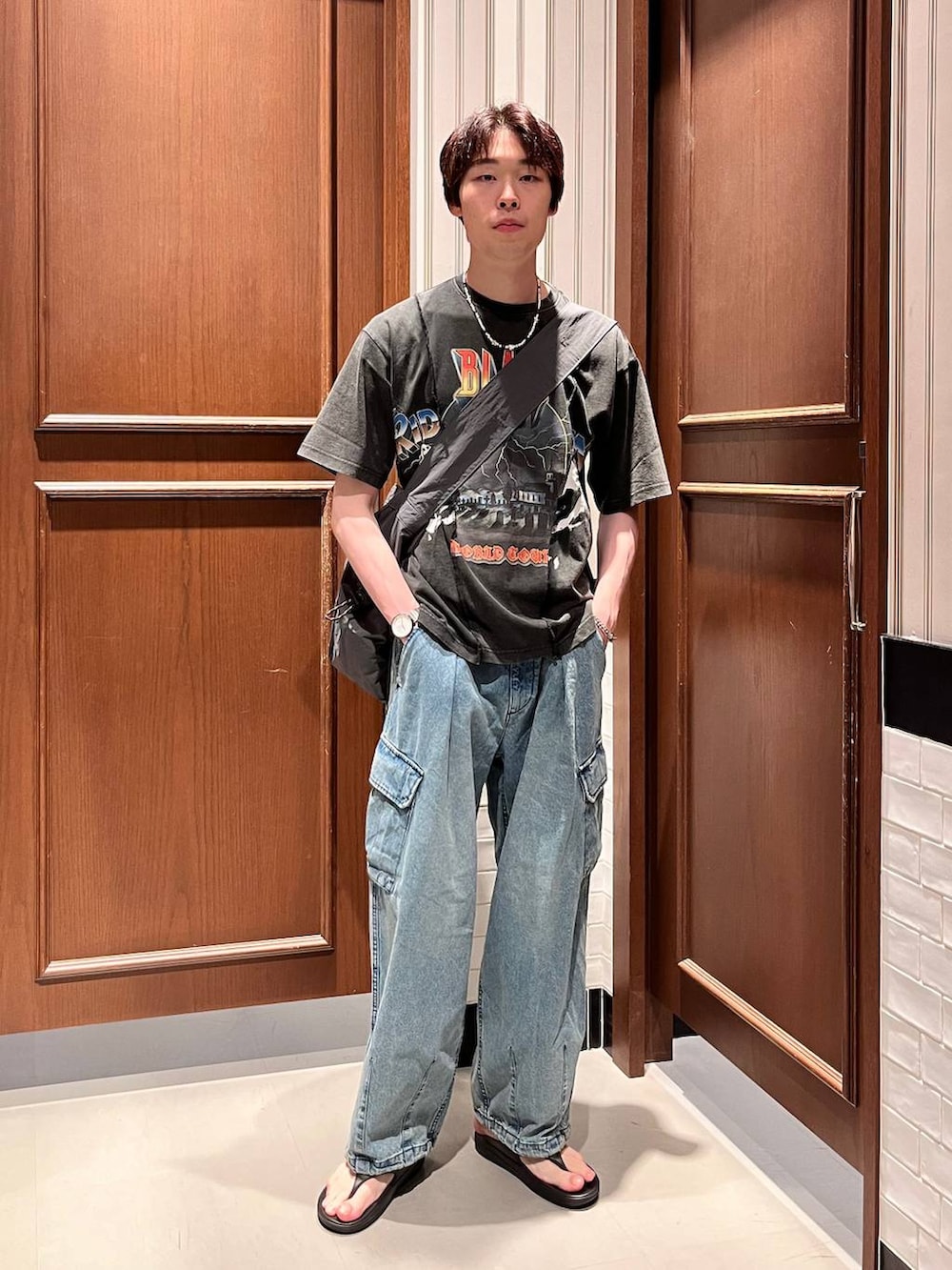 ブラック系のサンダル、ブルー系のデニムパンツ、ブラック系のショルダーバッグを着用したメンズの夏コーディネートの3枚目の写真