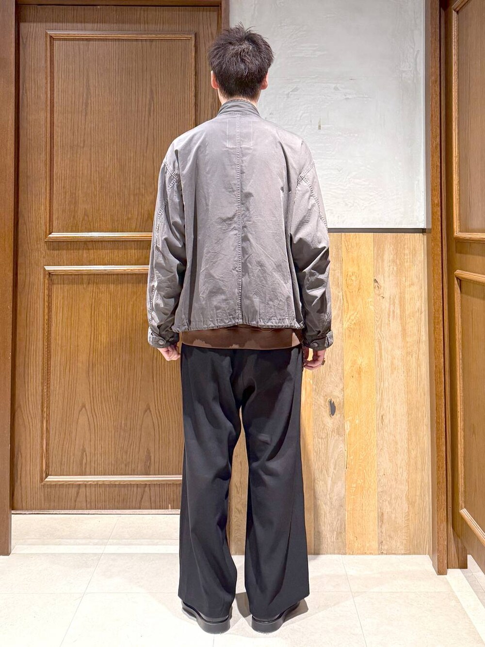 グレー系のモッズコート、ブラック系のスラックス、ブラウン系のスウェットを着用したメンズの秋コーディネートの5枚目の写真