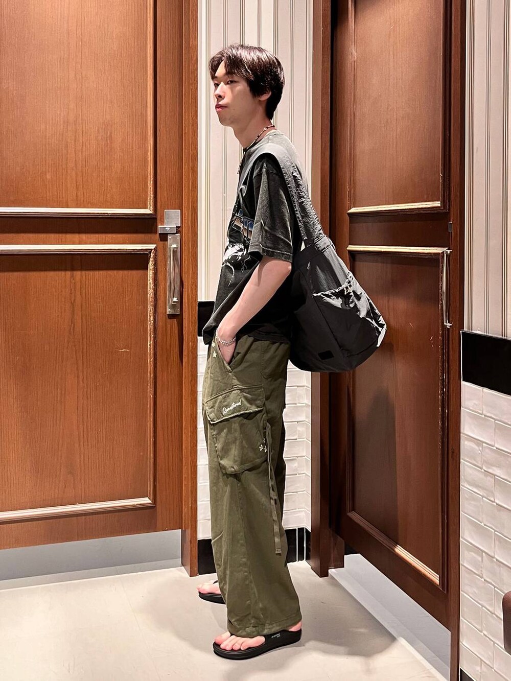 ブラック系のサンダル、グリーン系のカーゴパンツ、グレー系のショルダーバッグを着用したメンズの夏コーディネートの3枚目の写真