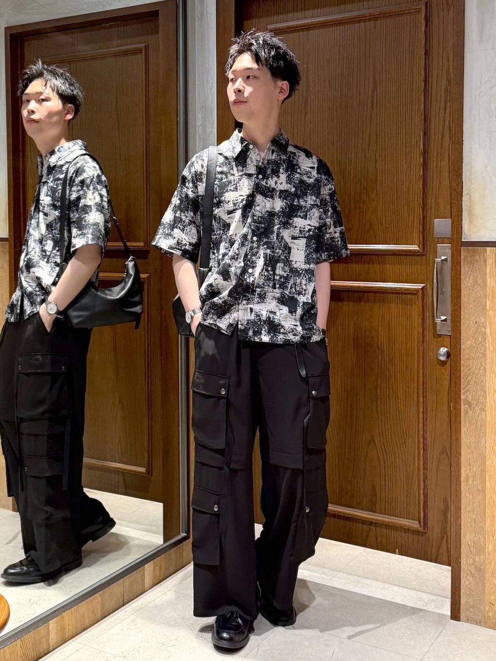 ブラック系のショルダーバッグ、ホワイト系のシャツ/ブラウス、ブラック系のカーゴパンツを着用したメンズの春コーディネートの2枚目の写真