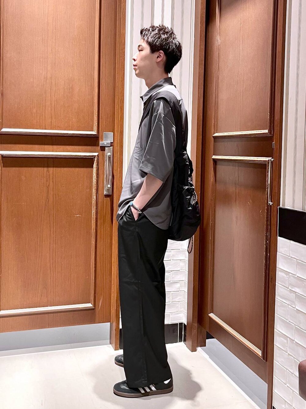 ブラック系のスラックス、グレー系のシャツ/ブラウス、ブラック系のショルダーバッグを着用したメンズの夏コーディネートの4枚目の写真