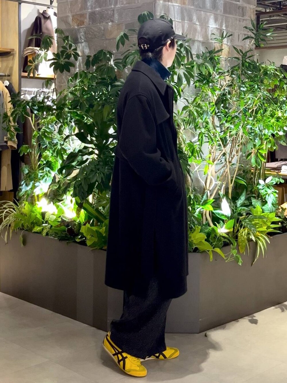 ブラック系のトレンチコート、ブルー系のニット/セーター、グレー系のスラックスを着用したメンズの秋コーディネートの2枚目の写真