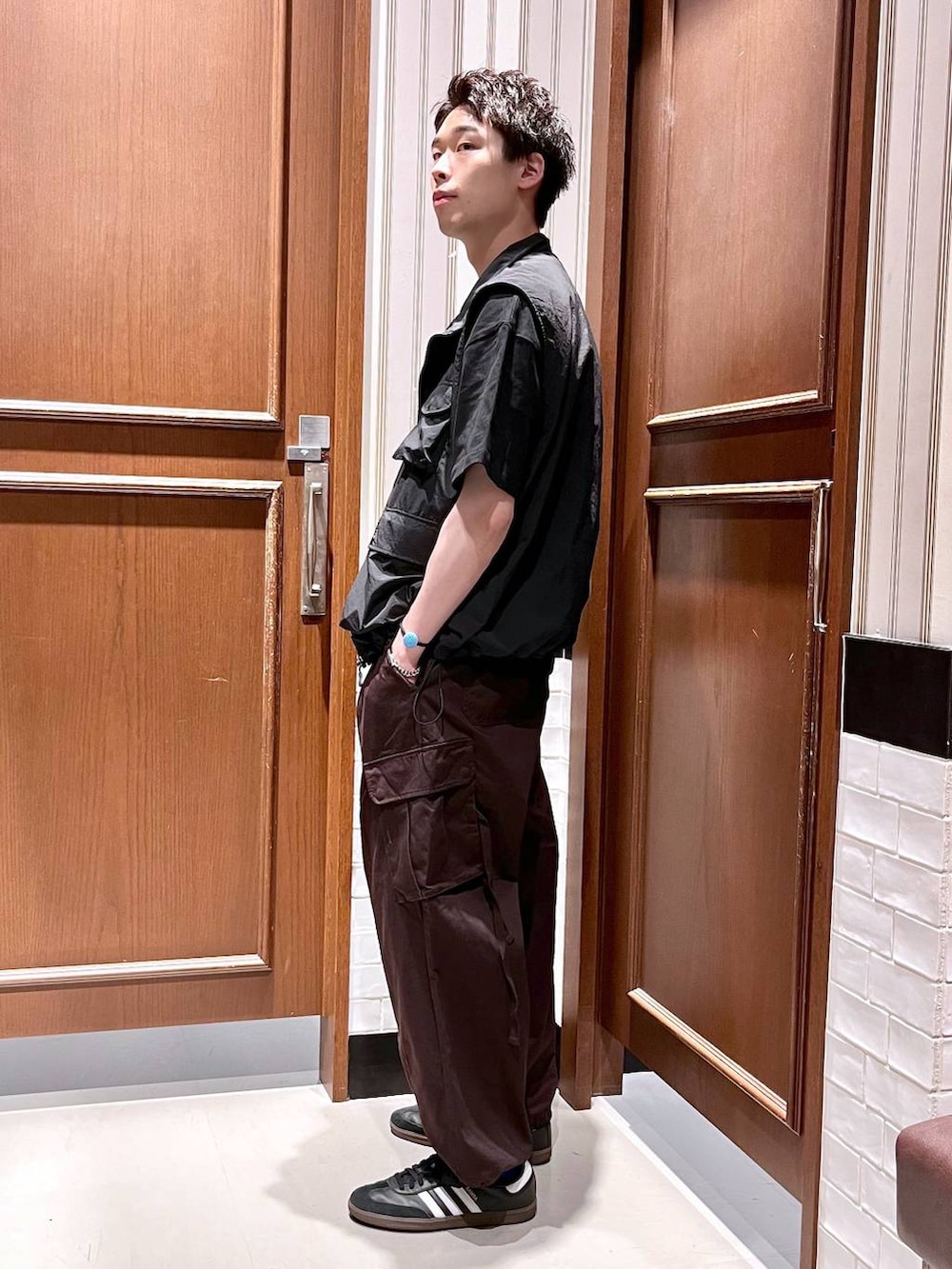 ブラウン系のカーゴパンツ、ブラック系のベスト、ブラック系のTシャツ/カットソーを着用したメンズの夏コーディネートの3枚目の写真