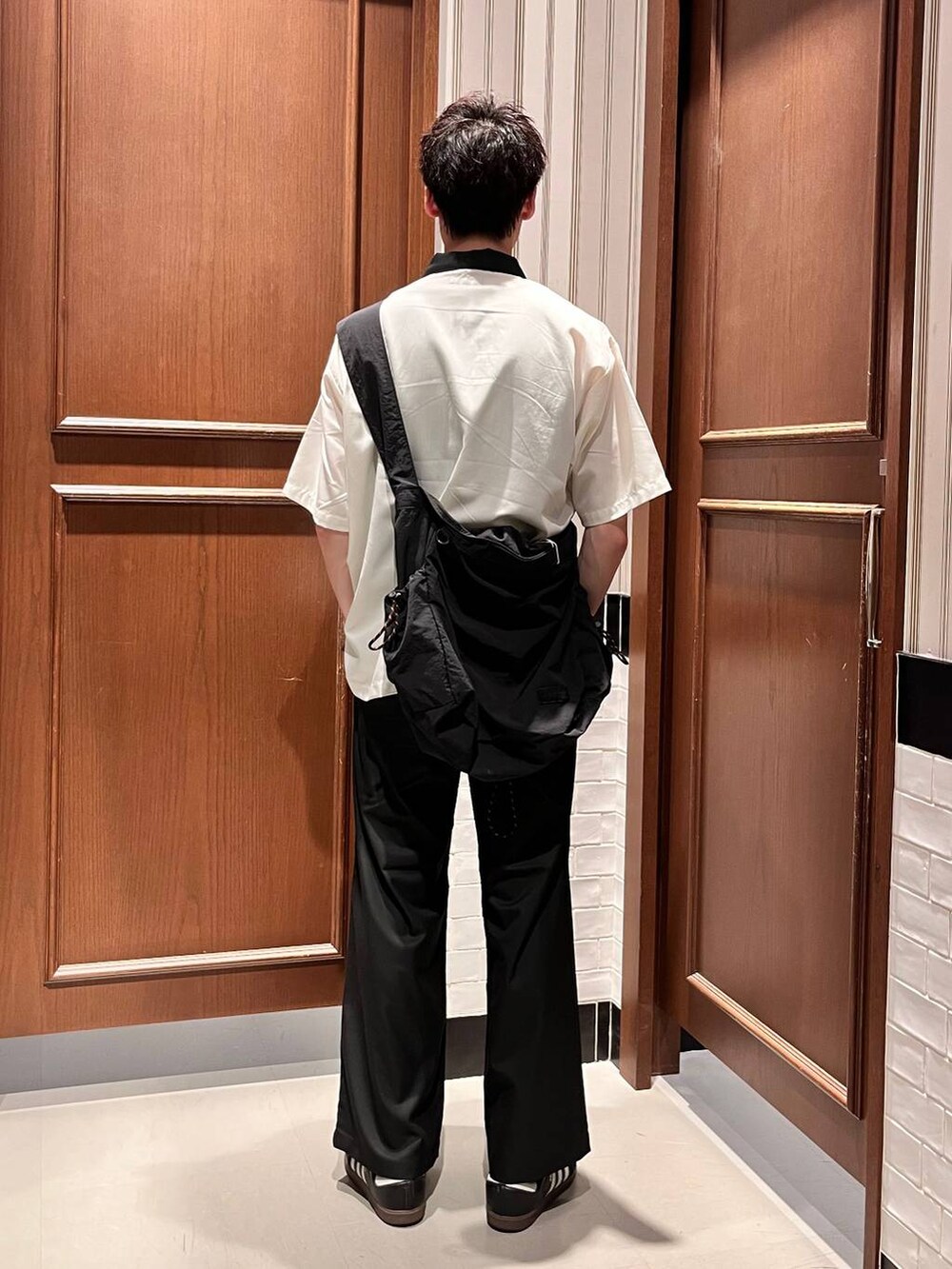 ブラック系のスラックス、ブラック系のショルダーバッグ、ホワイト系のシャツ/ブラウスを着用したメンズの夏コーディネートの4枚目の写真