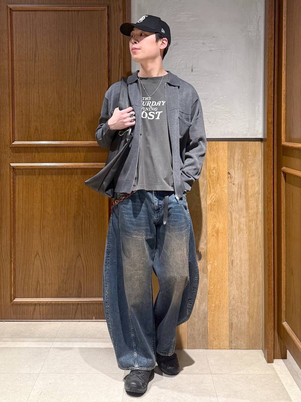 ブラック系のトートバッグ、ブルー系のデニムパンツ、グレー系のTシャツ/カットソーを着用したメンズの春コーディネートの6枚目の写真