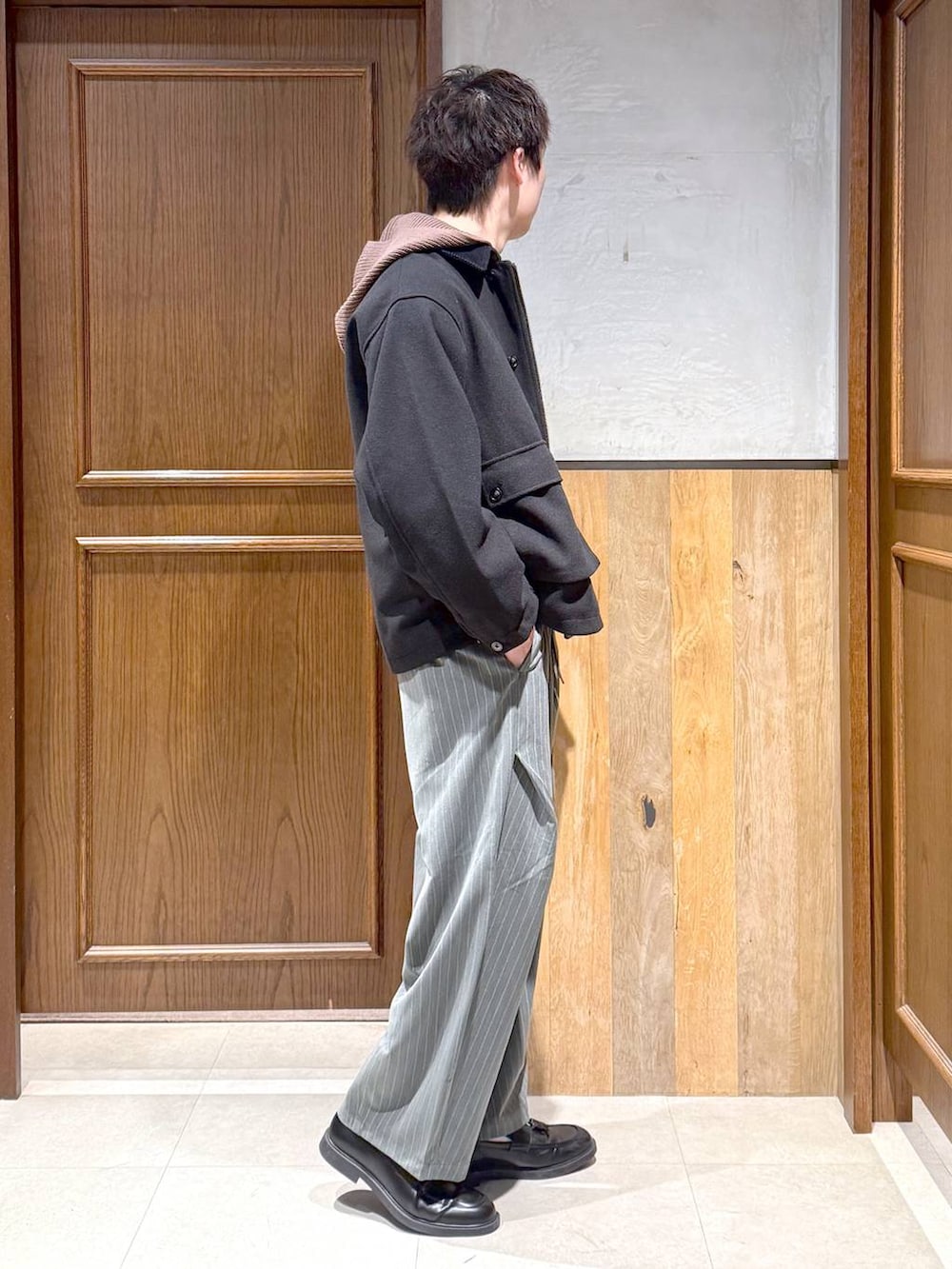 ブラック系のブルゾン、ブラウン系のニット/セーター、グレー系のスラックスを着用したメンズの冬コーディネートの4枚目の写真