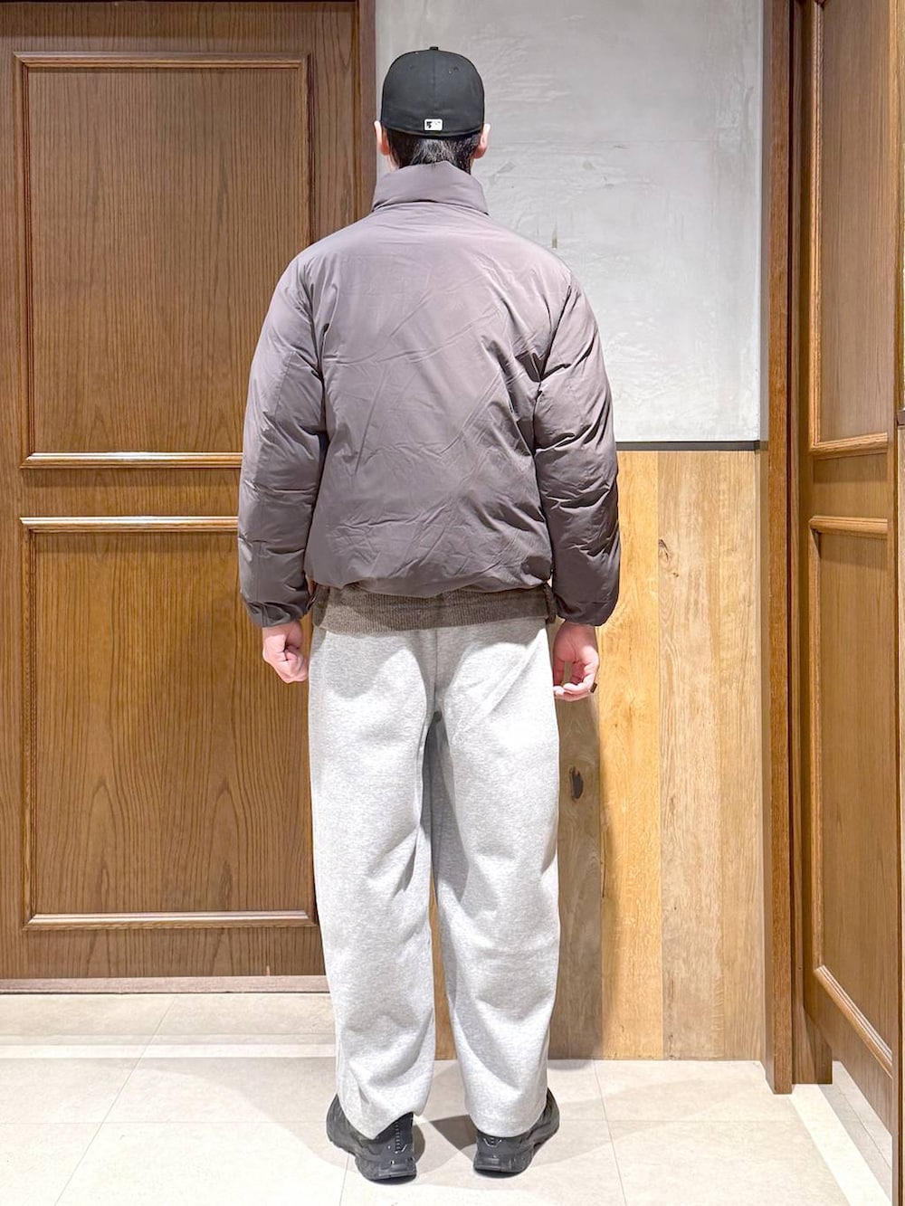 グレー系のダウンジャケット/コート、ベージュ系のポロシャツ、グレー系のスウェットパンツを着用したメンズの冬コーディネートの6枚目の写真