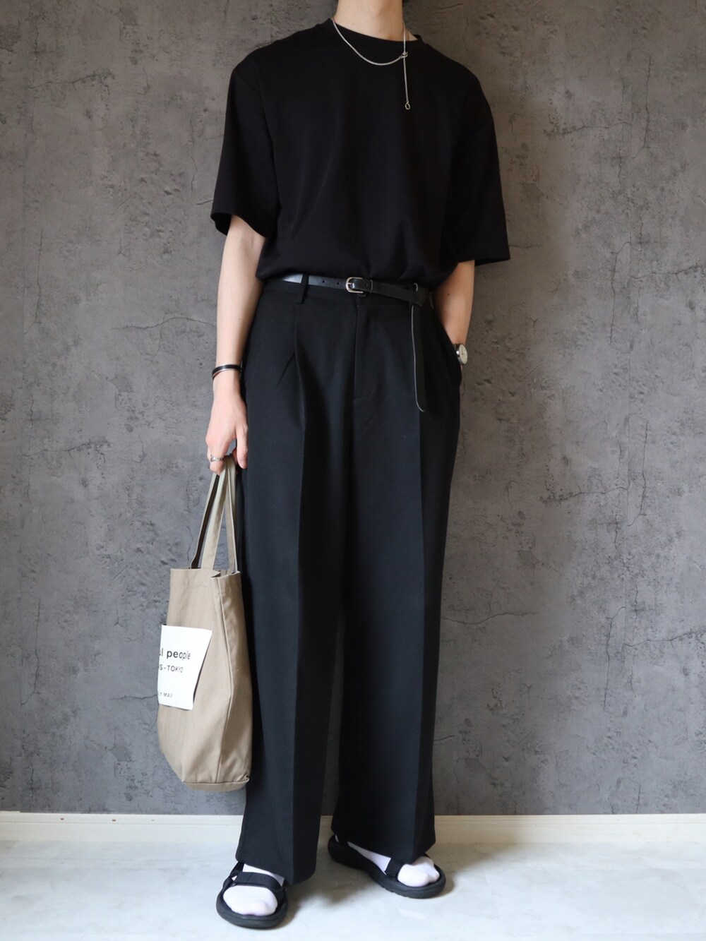 ブラック系のスラックス、ベージュ系のトートバッグ、ブラック系のサンダルを着用したメンズの夏コーディネートの4枚目の写真