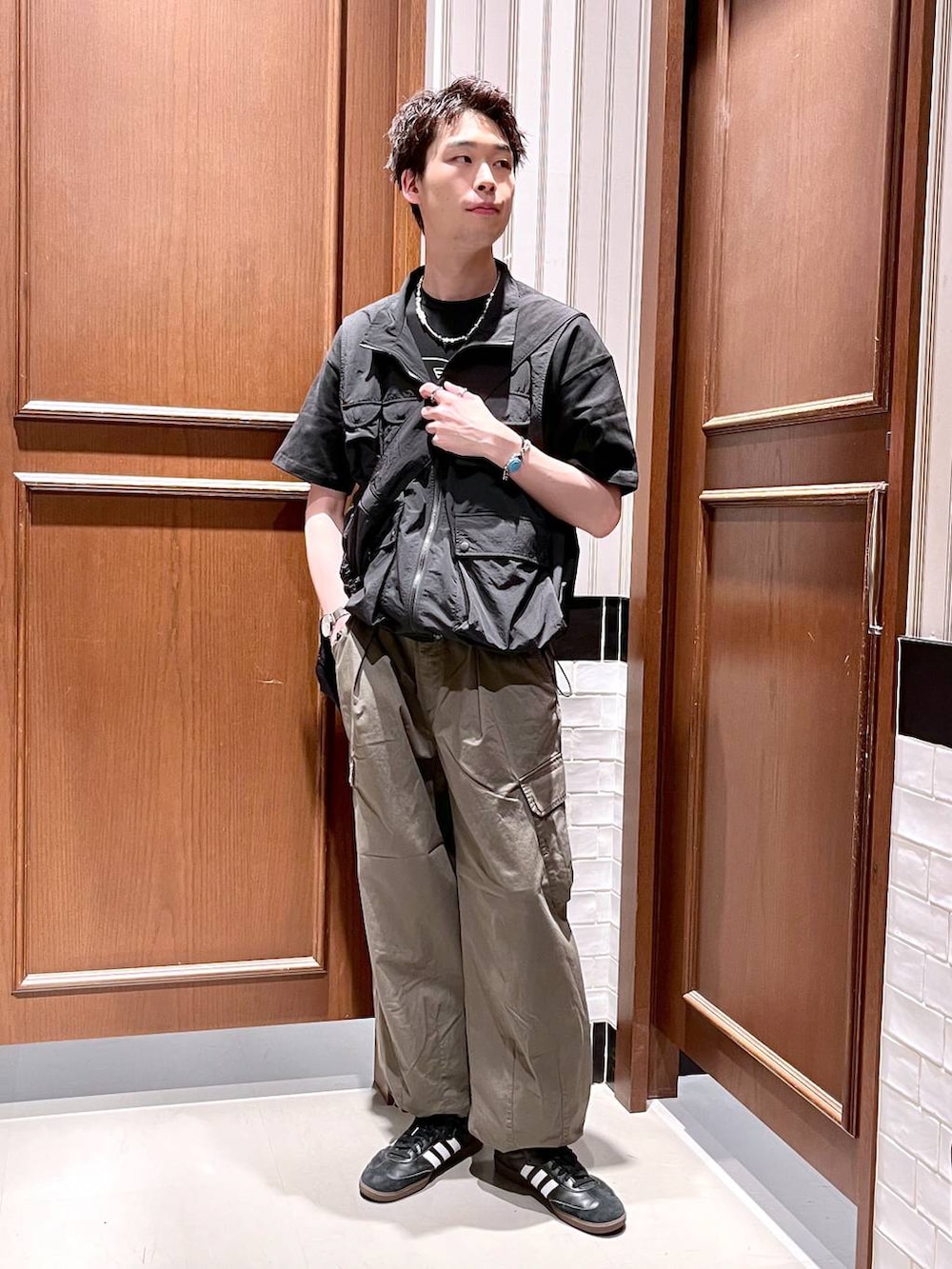 グリーン系のカーゴパンツ、ブラック系のショルダーバッグ、ブラック系のベストを着用したメンズの夏コーディネートの3枚目の写真