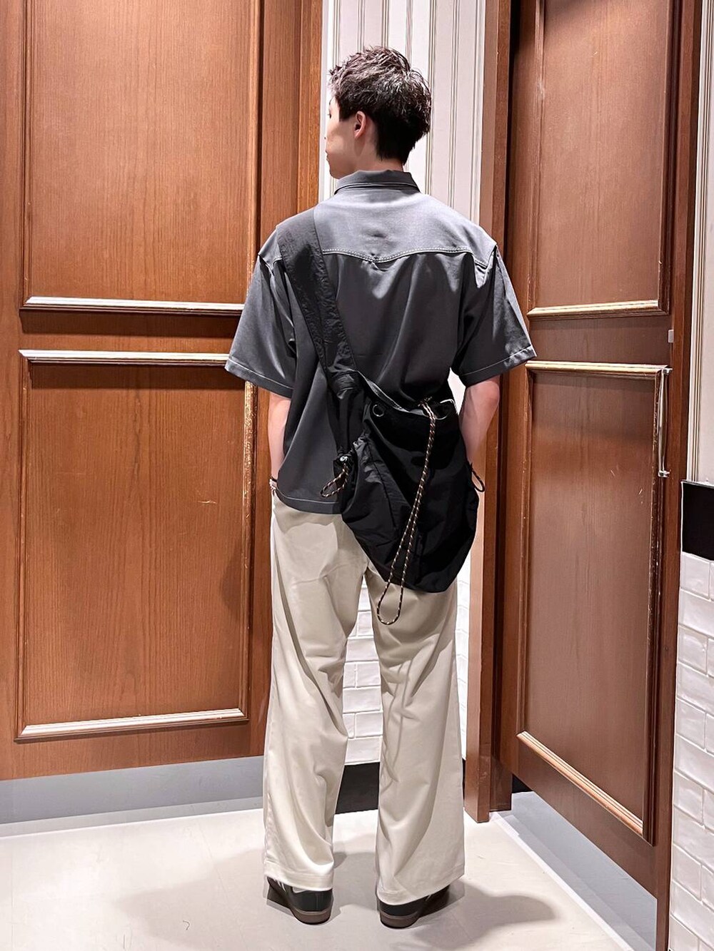 ホワイト系のスラックス、ブラック系のショルダーバッグ、グレー系のシャツ/ブラウスを着用したメンズの夏コーディネートの4枚目の写真