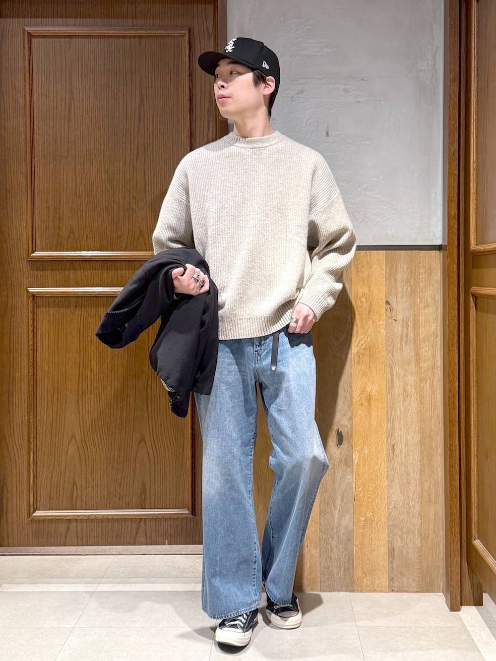 ブラック系のブルゾン、ホワイト系のニット/セーター、ブルー系のデニムパンツを着用したメンズの冬コーディネートの2枚目の写真