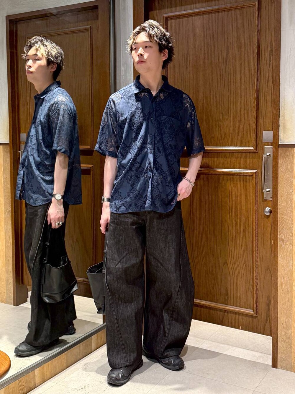 ブラック系のハンドバッグ、ブラック系のデニムパンツ、ブルー系のシャツ/ブラウスを着用したメンズの春コーディネートの5枚目の写真