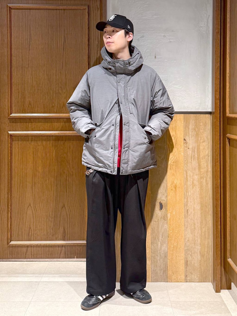 グレー系のダウンジャケット/コート、ブラック系のスラックス、レッド系のスウェットを着用したメンズの冬コーディネートの2枚目の写真