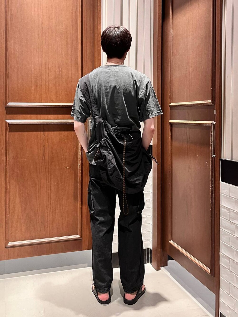 ブラック系のサンダル、グレー系のデニムパンツ、ブラック系のショルダーバッグを着用したメンズの夏コーディネートの3枚目の写真