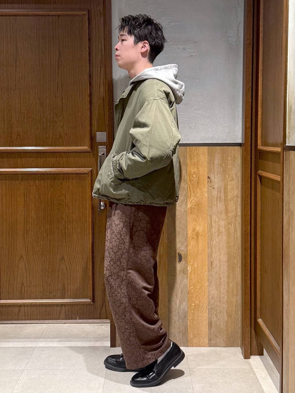 グリーン系のモッズコート、イエロー系のスラックス、グレー系のパーカーを着用したメンズの冬コーディネートの4枚目の写真