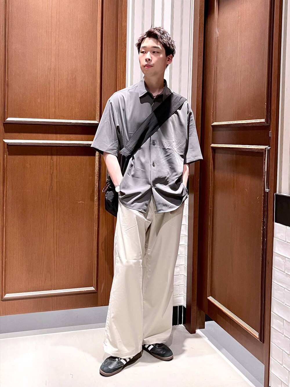 ホワイト系のスラックス、グレー系のシャツ/ブラウス、ブラック系のショルダーバッグを着用したメンズの夏コーディネートの2枚目の写真