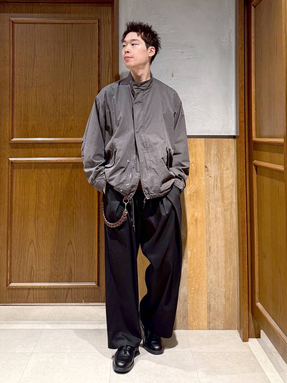 グレー系のモッズコート、ブラック系のスラックス、ブラウン系のスウェットを着用したメンズの秋コーディネートの3枚目の写真