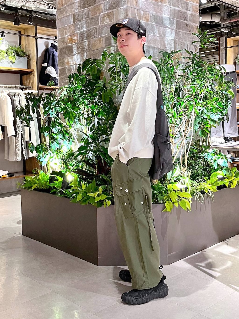 グリーン系のカーゴパンツ、その他のショルダーバッグ、ホワイト系のニット/セーターを着用したメンズの春コーディネートの5枚目の写真