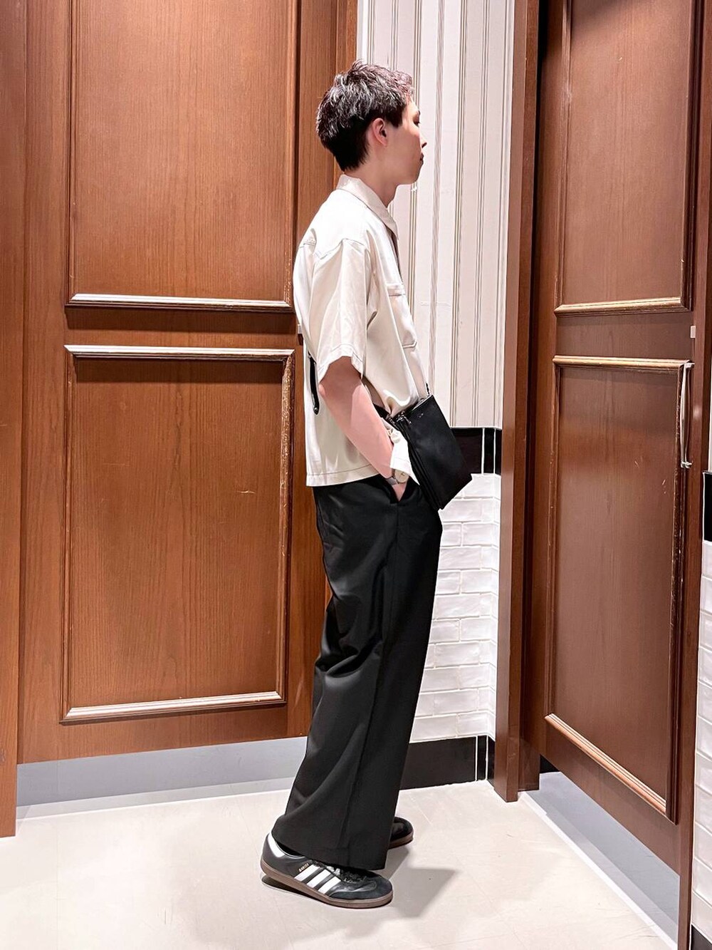 ブラック系のスラックス、ブラック系のショルダーバッグ、ホワイト系のシャツ/ブラウスを着用したメンズの夏コーディネートの3枚目の写真