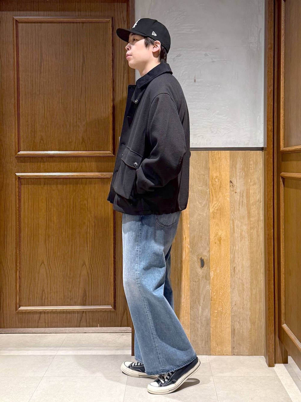 ブラック系のブルゾン、ホワイト系のニット/セーター、ブルー系のデニムパンツを着用したメンズの冬コーディネートの4枚目の写真