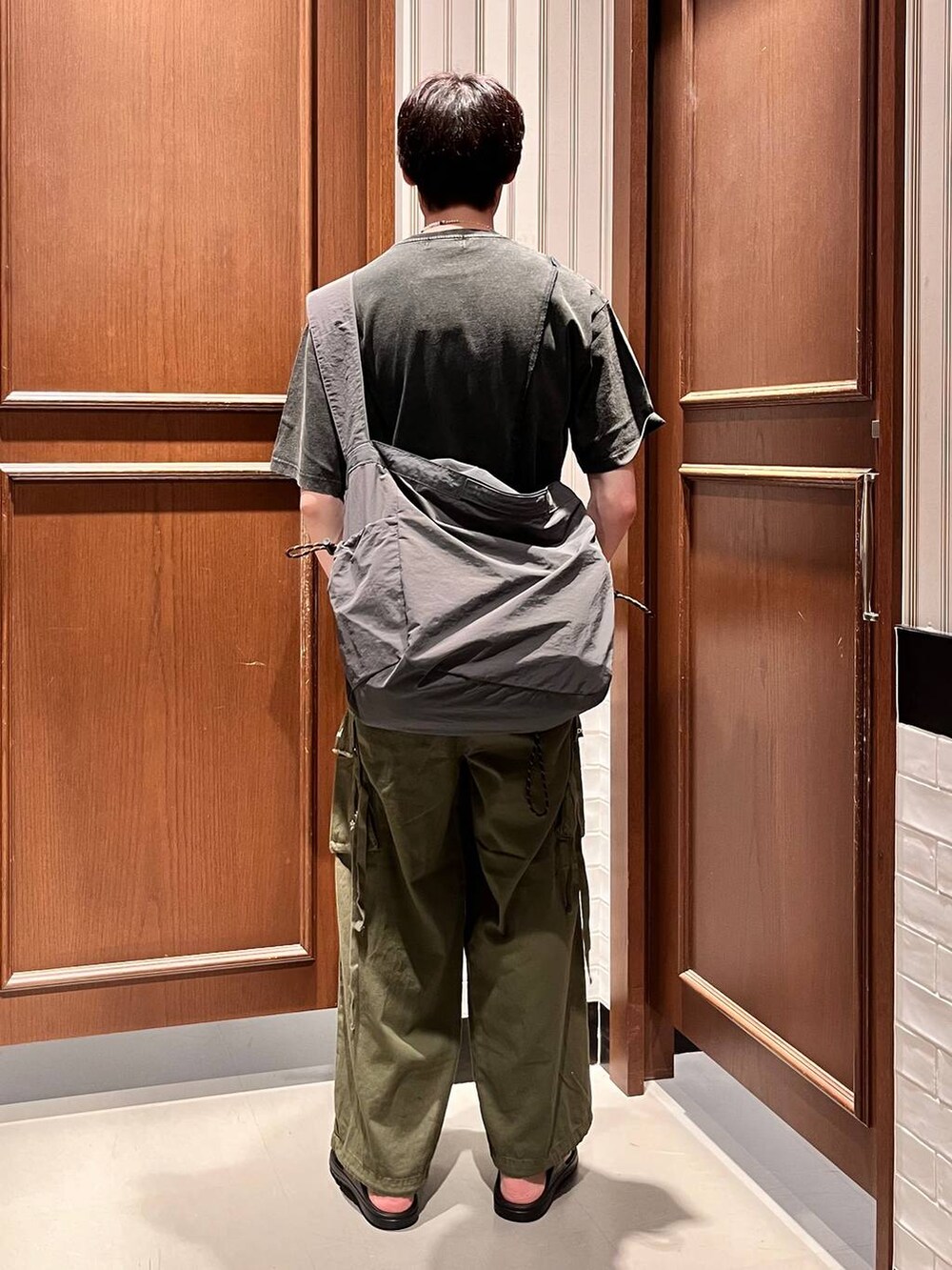 ブラック系のサンダル、グリーン系のカーゴパンツ、グレー系のショルダーバッグを着用したメンズの夏コーディネートの5枚目の写真