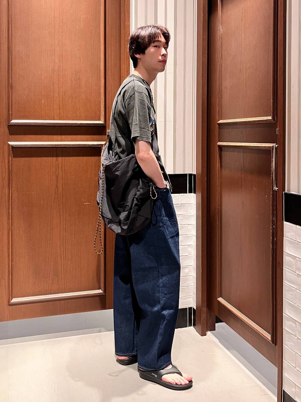 ブラック系のサンダル、ブルー系のデニムパンツ、ブラック系のショルダーバッグを着用したメンズの夏コーディネートの3枚目の写真