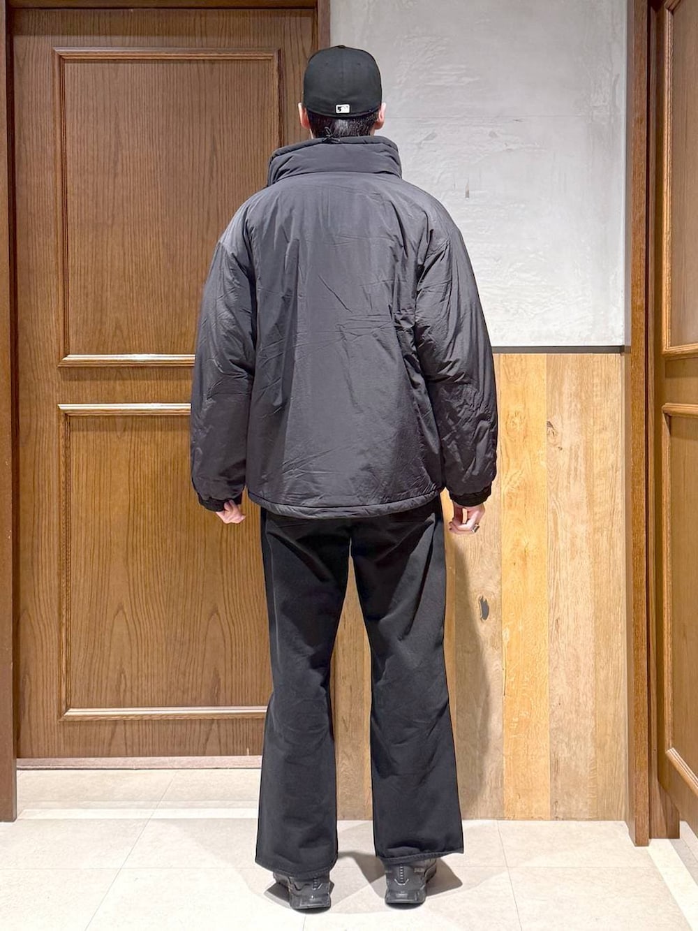 ブラック系のデニムパンツ、グリーン系のニット/セーター、ブラック系のダウンジャケット/コートを着用したメンズの冬コーディネートの6枚目の写真