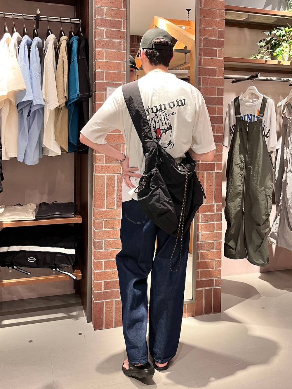 ブルー系のデニムパンツ、ブラック系のショルダーバッグ、ホワイト系のTシャツ/カットソーを着用したメンズの夏コーディネートの3枚目の写真