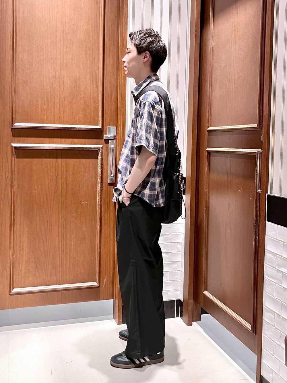 ブラック系のスラックス、ブラック系のショルダーバッグ、ブルー系のシャツ/ブラウスを着用したメンズの夏コーディネートの3枚目の写真