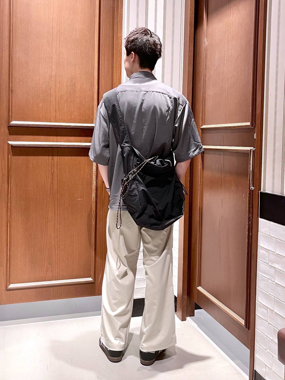 ホワイト系のスラックス、グレー系のシャツ/ブラウス、ブラック系のショルダーバッグを着用したメンズの夏コーディネートの4枚目の写真