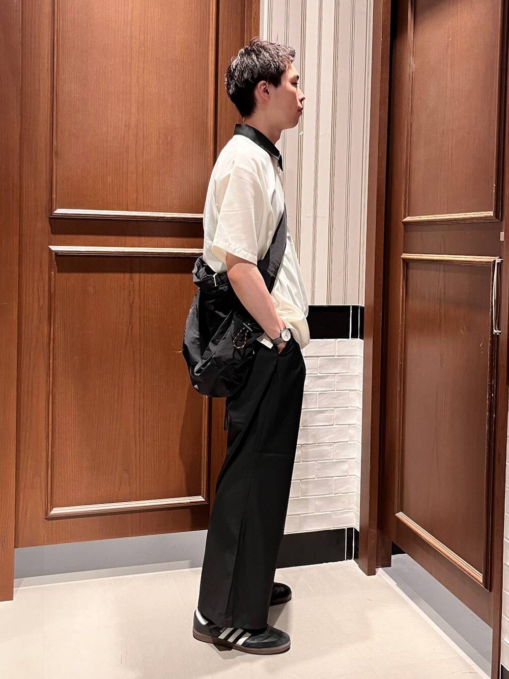ブラック系のスラックス、ブラック系のショルダーバッグ、ホワイト系のシャツ/ブラウスを着用したメンズの夏コーディネートの5枚目の写真